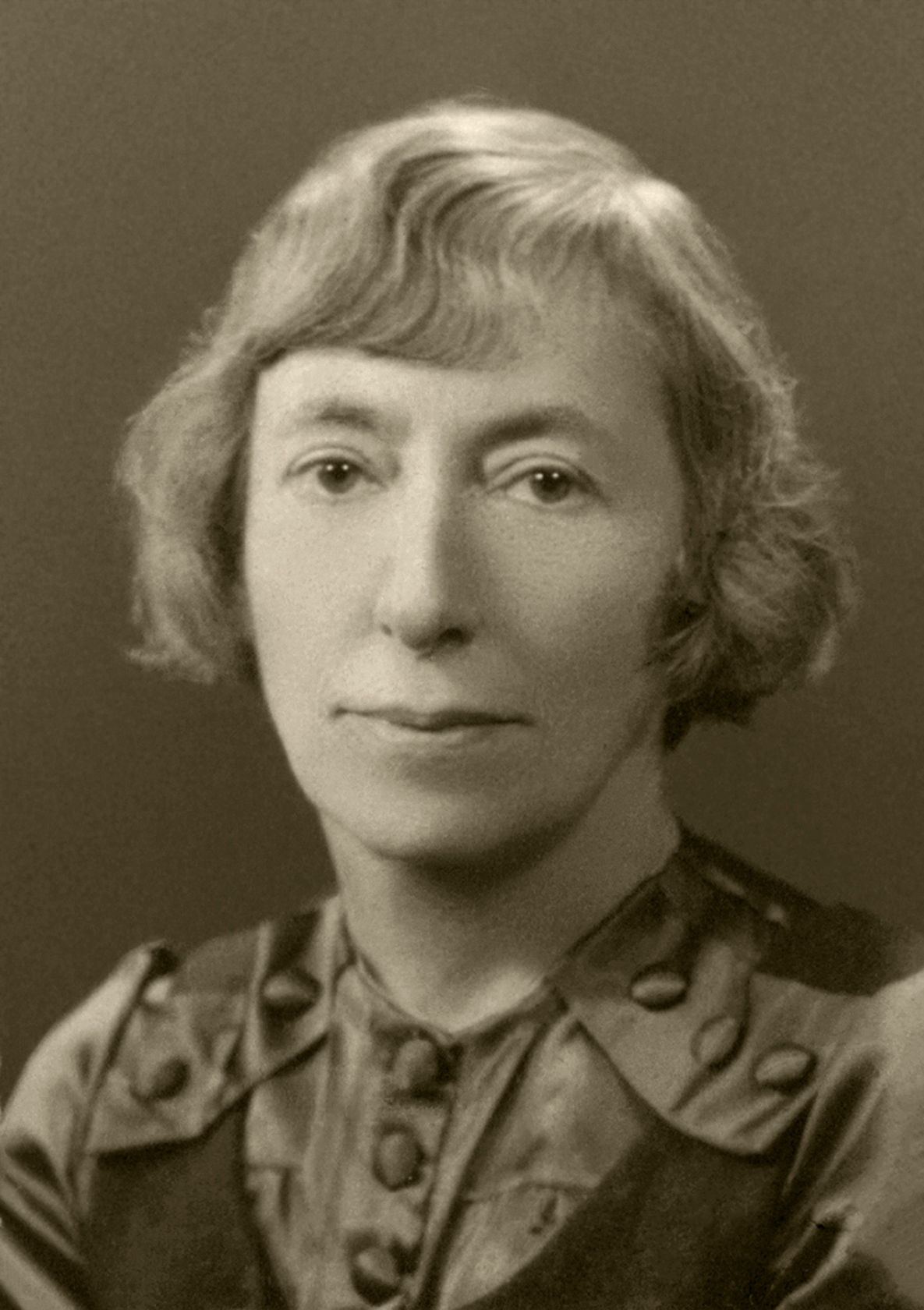 zdjecie w sepi, młoda kobieta w eleganckiej bluzce pozuje do portretowego zdjęcia