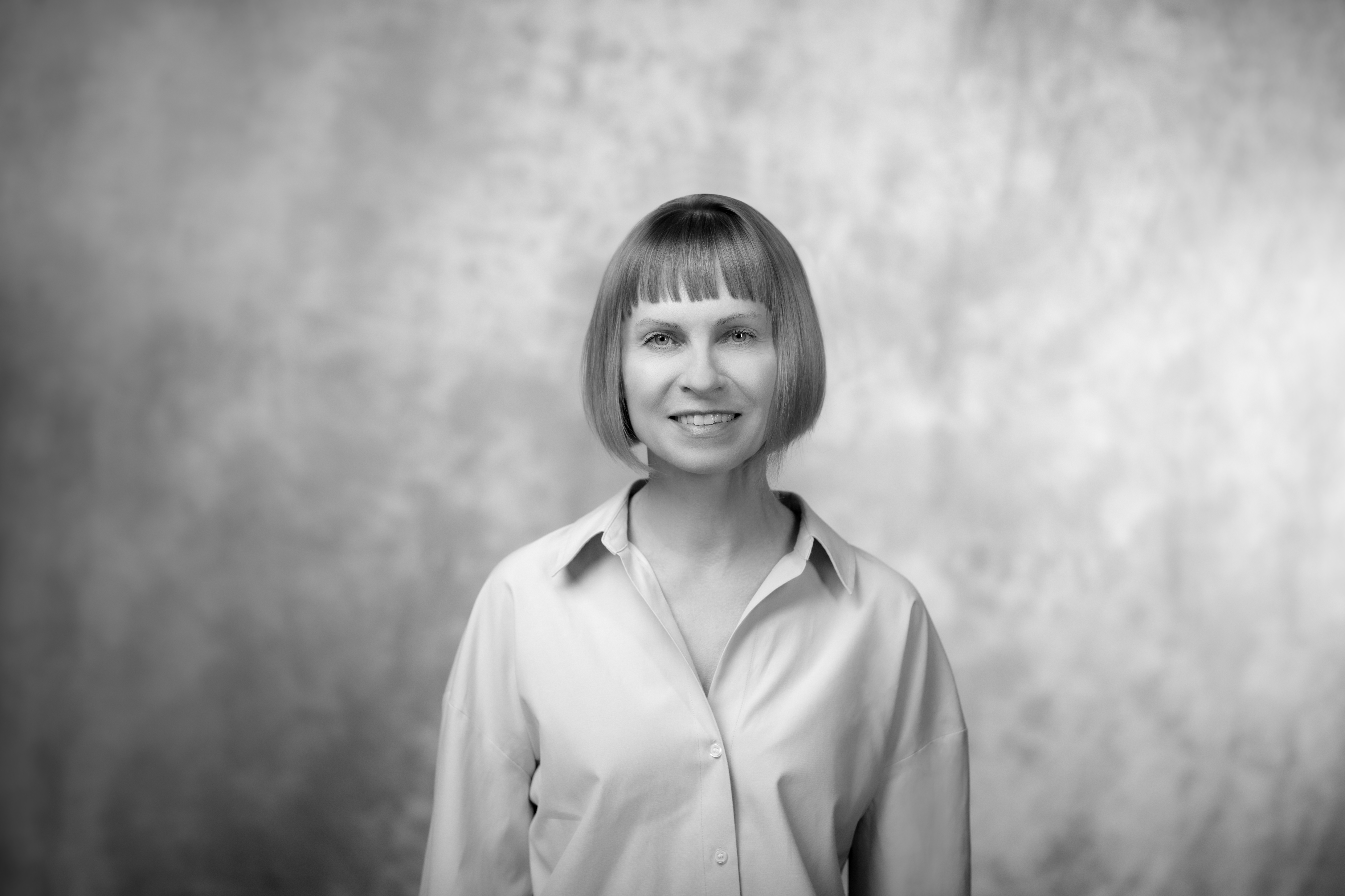 czarno-białę zdjęcie młodej kobiety w jasnym stroju  na tle szarek ściany