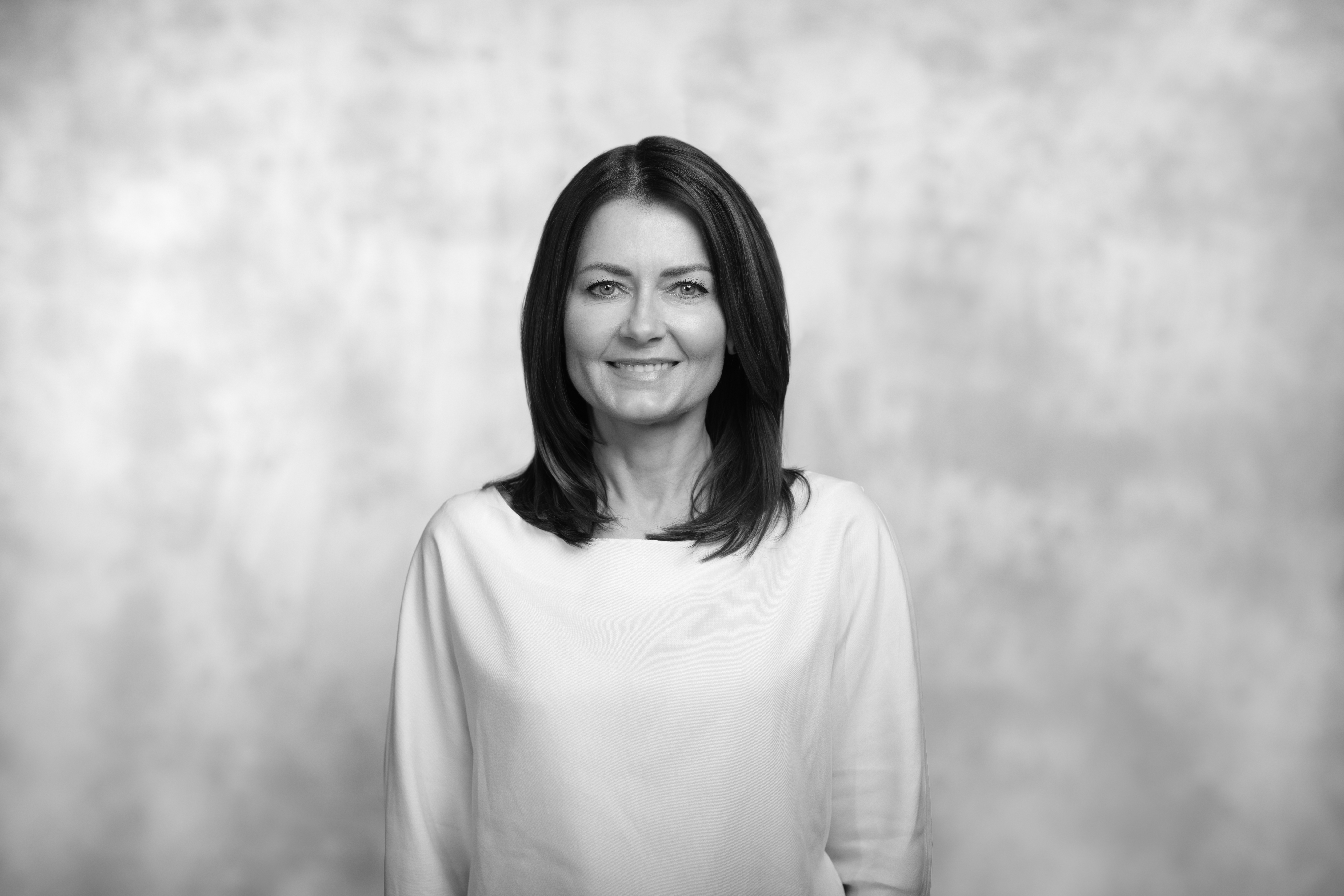 czarno-biały portret kobiety e jasnej bluzce, rozpuszczone ciemne włosy i delikatny uśmiech