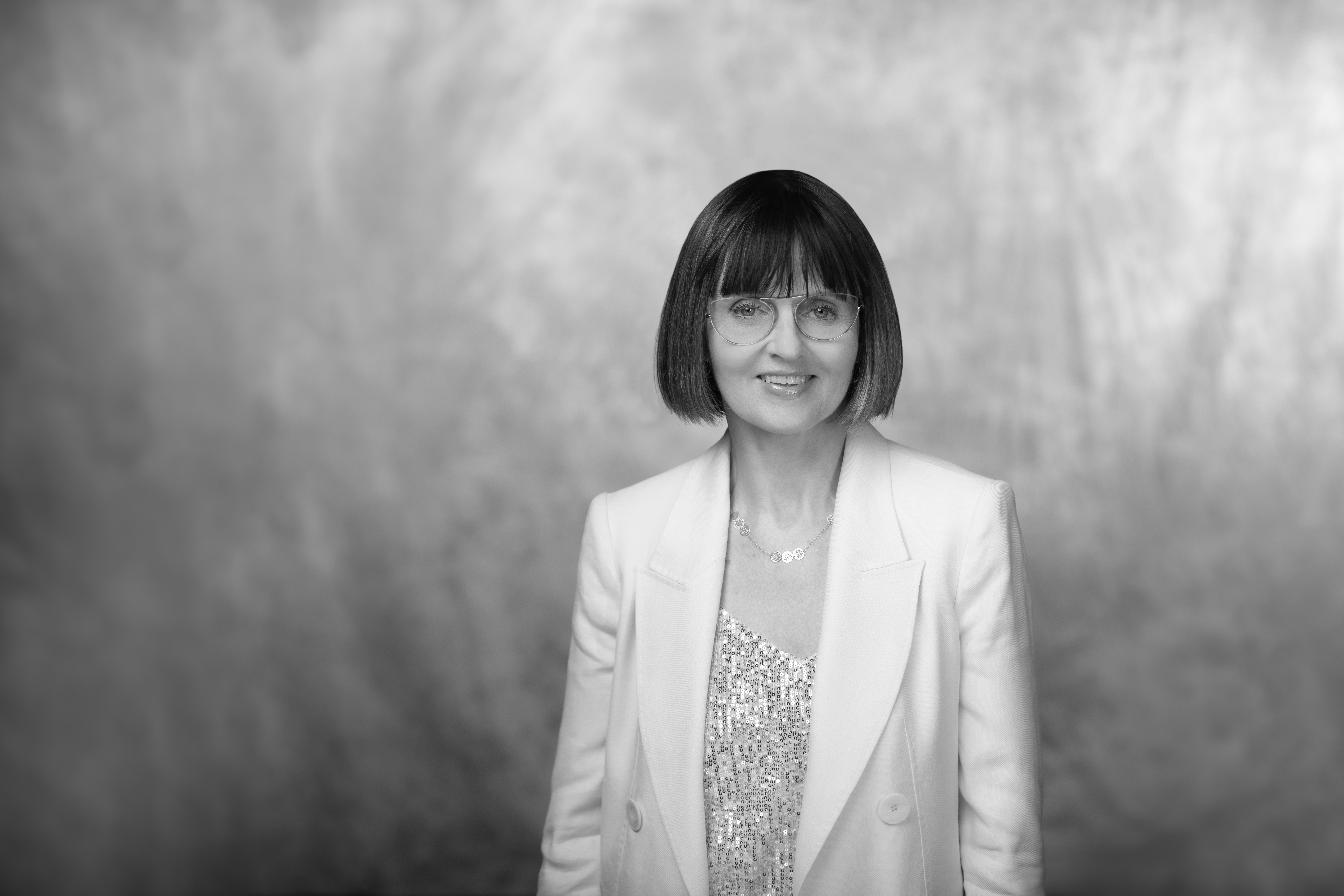 czarno-biały portret kobiety w dojrzałym wieku, rozpuszczone kręcone jasne włosy i delikatny uśmiech