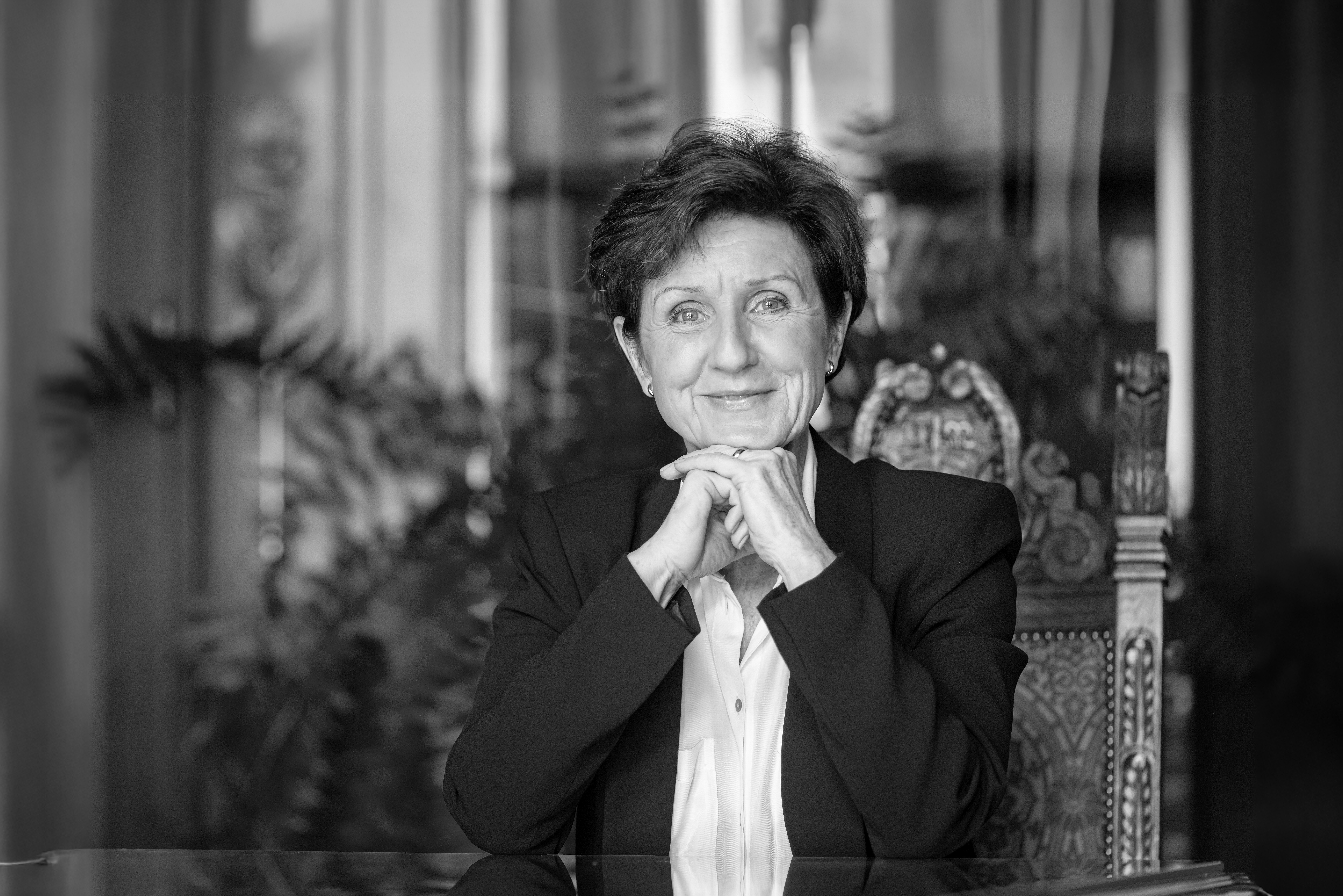 czarno-biały portret kobiety w dojrzałym wieku, podpierającej skrzyżowane dłonie o brodę