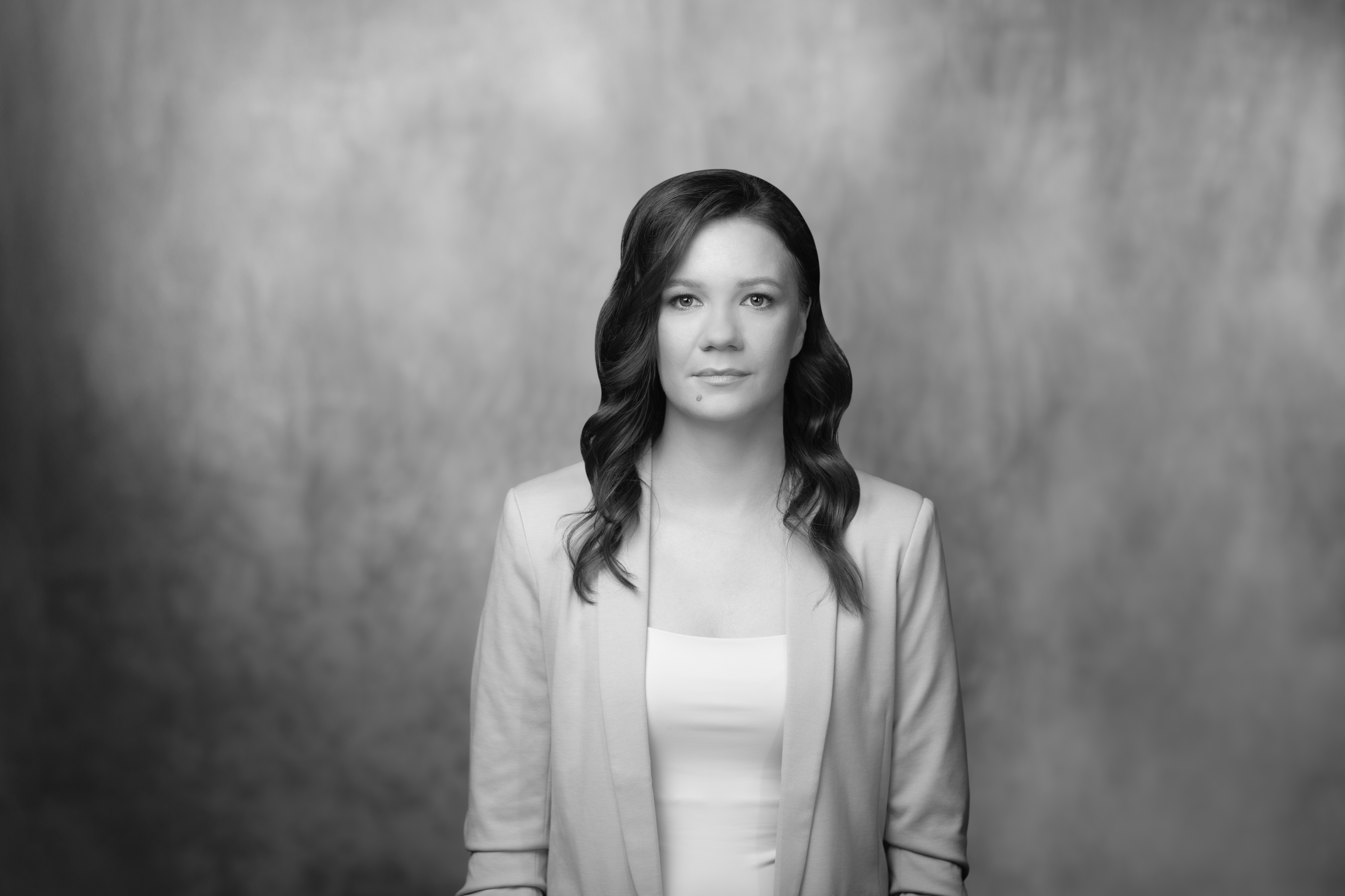 czarrno biały portret kobiety, uśmiechniętej, w jasnym żakiecie, rozpuszczonych włosach