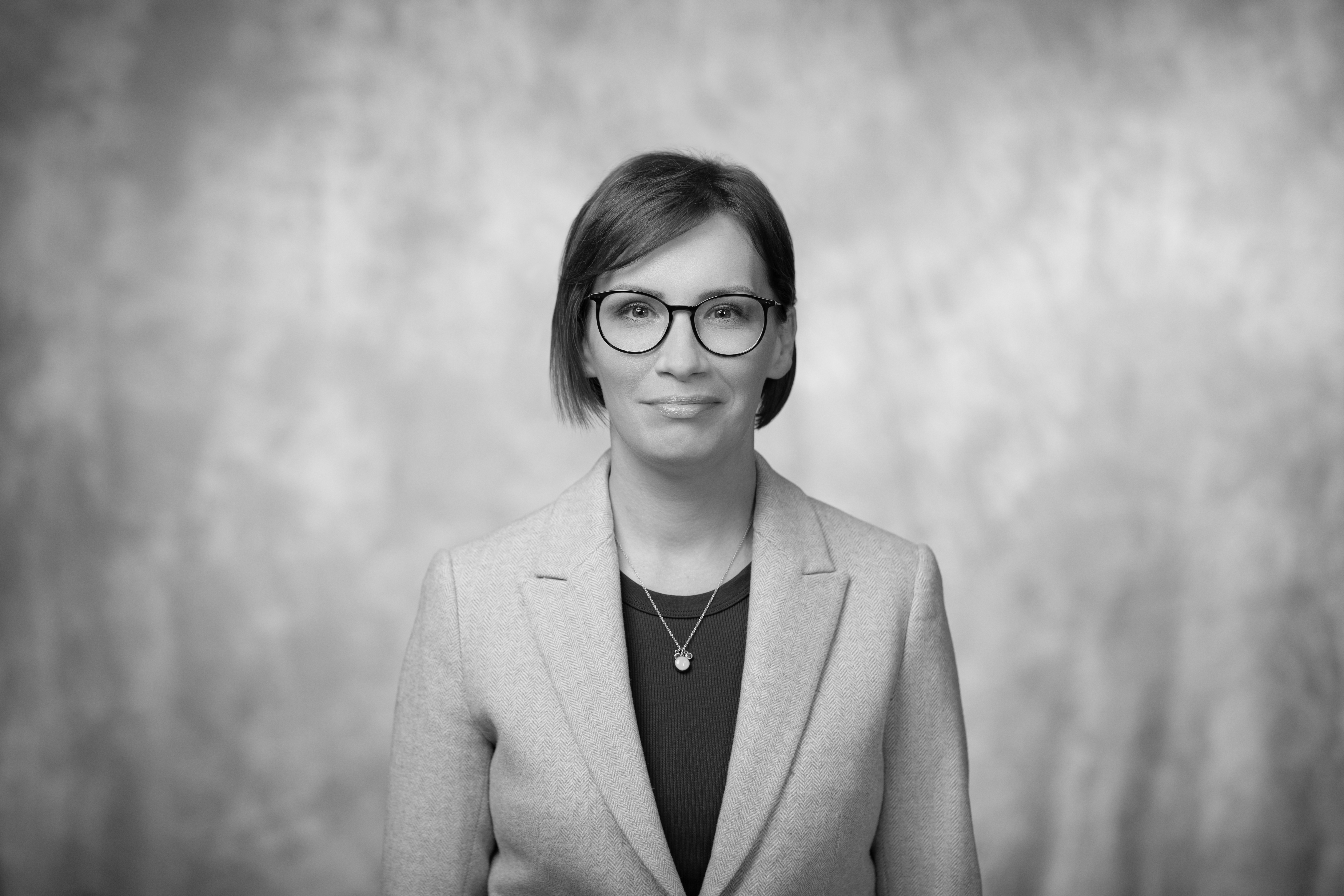 czarno-biały portret uśmiechniętej kobiety w okularach