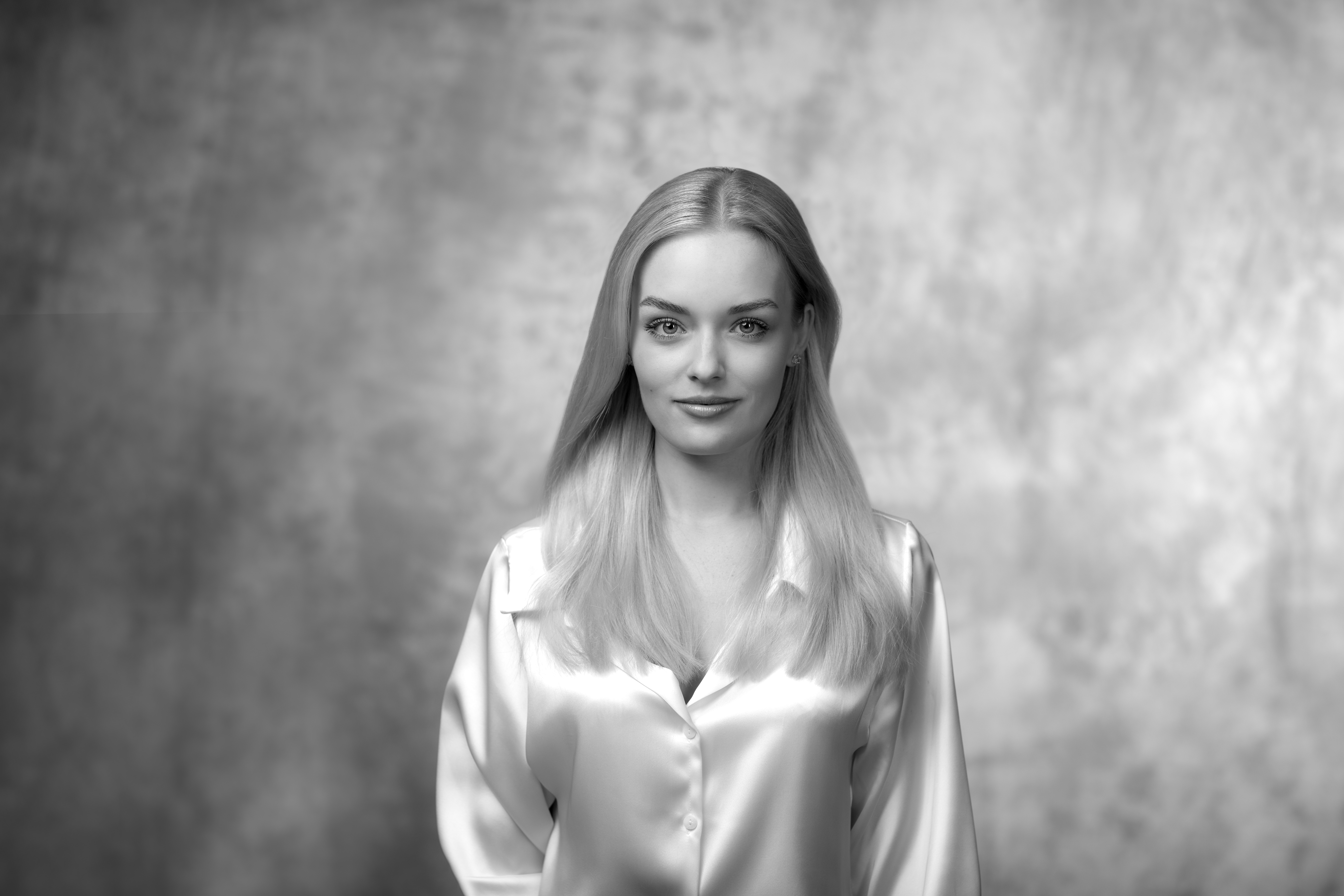 czarnobiały portret młodej kobiety w blond włosach, białej bluzce, patrzącej wprost do obiektywu z lekkim uśmiechem