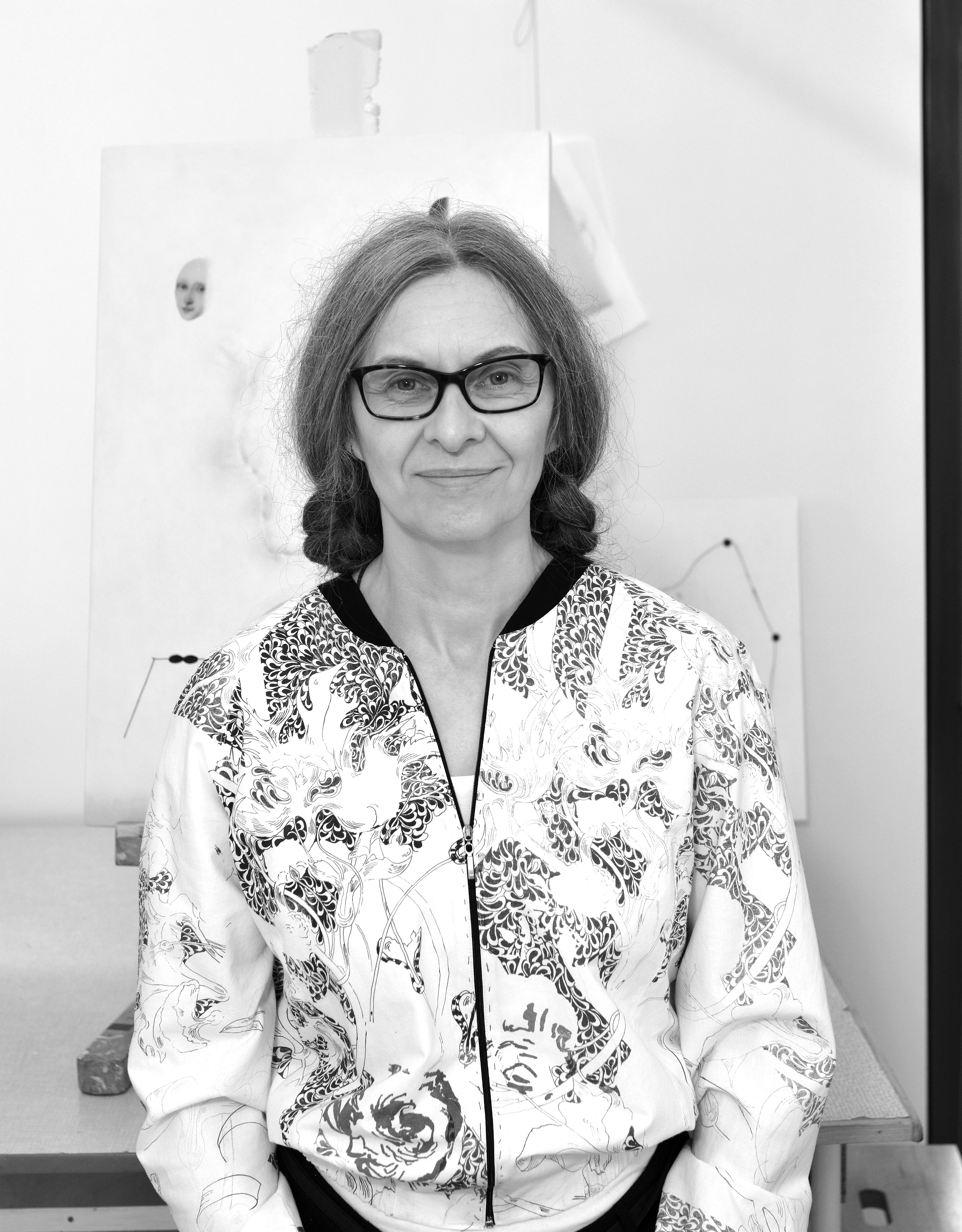 portret dojrzałej kobiety stojącej na białym tle, ubranej we wzorzystą kurtkę