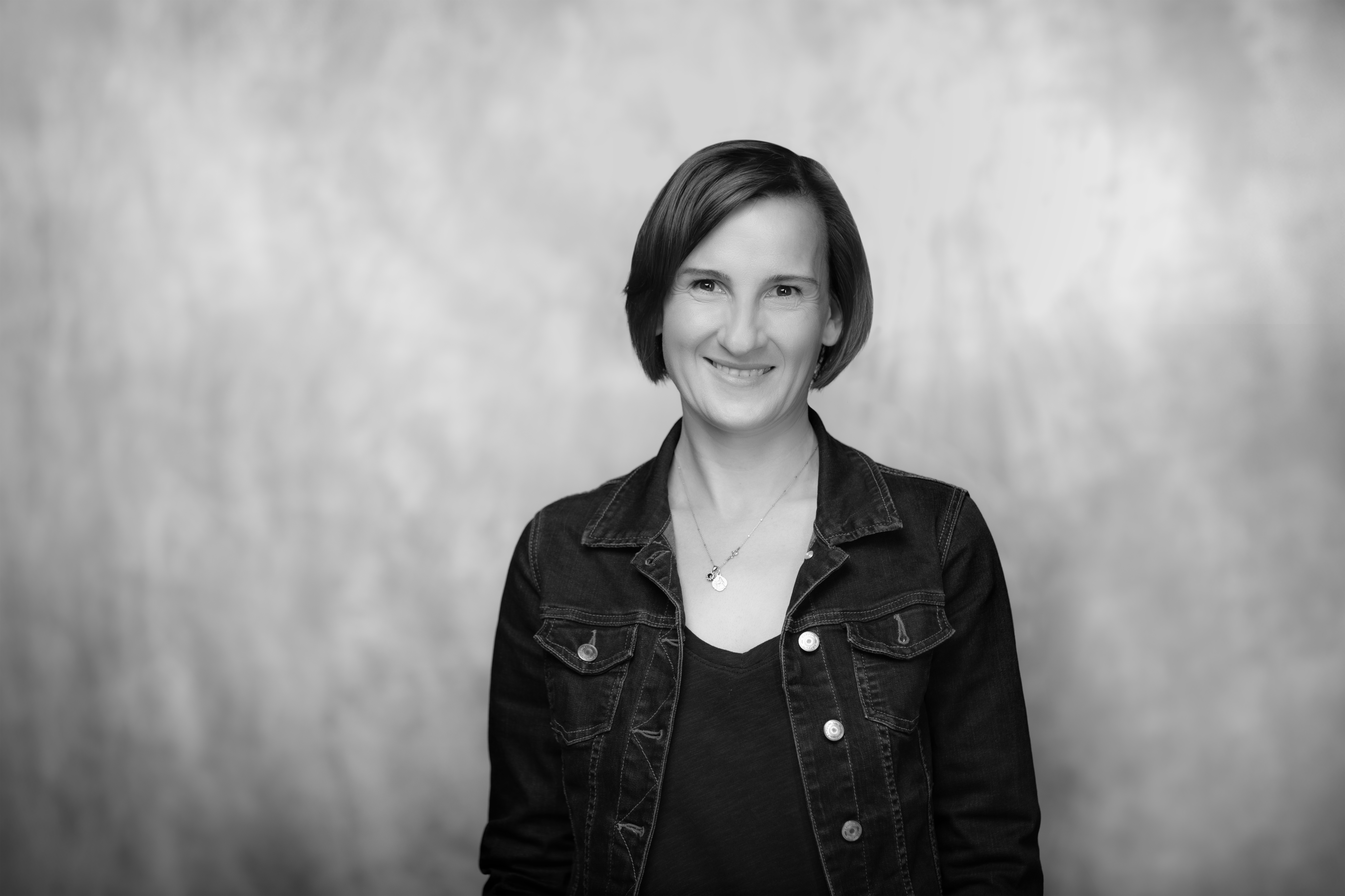 czarno-biały portret uśmiechniętej młodej kobiety w czarnej kurtce