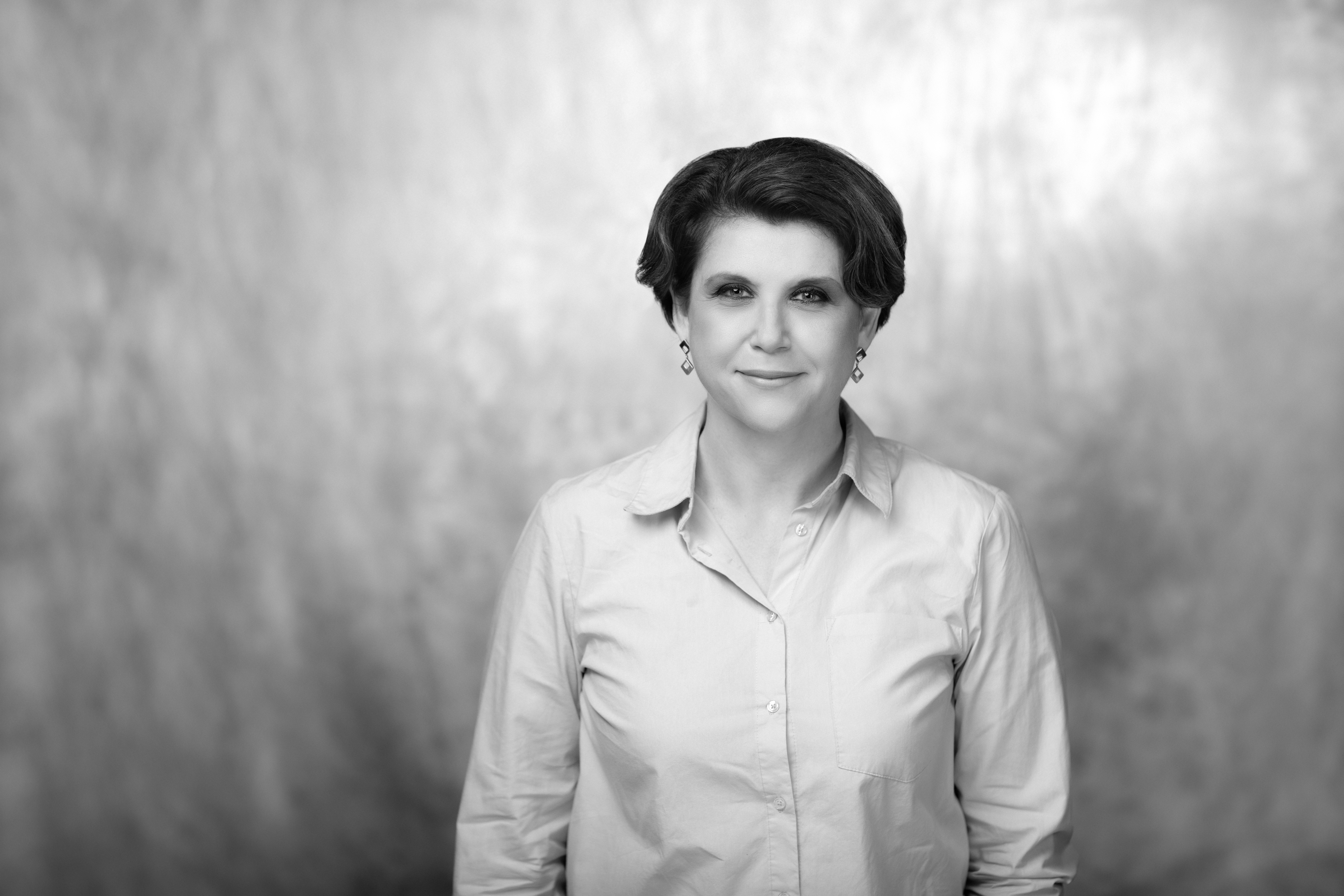 czarno-biały portret kobiety w dojrzałym wieku, rozpuszczone kręcone jasne włosy i delikatny uśmiech