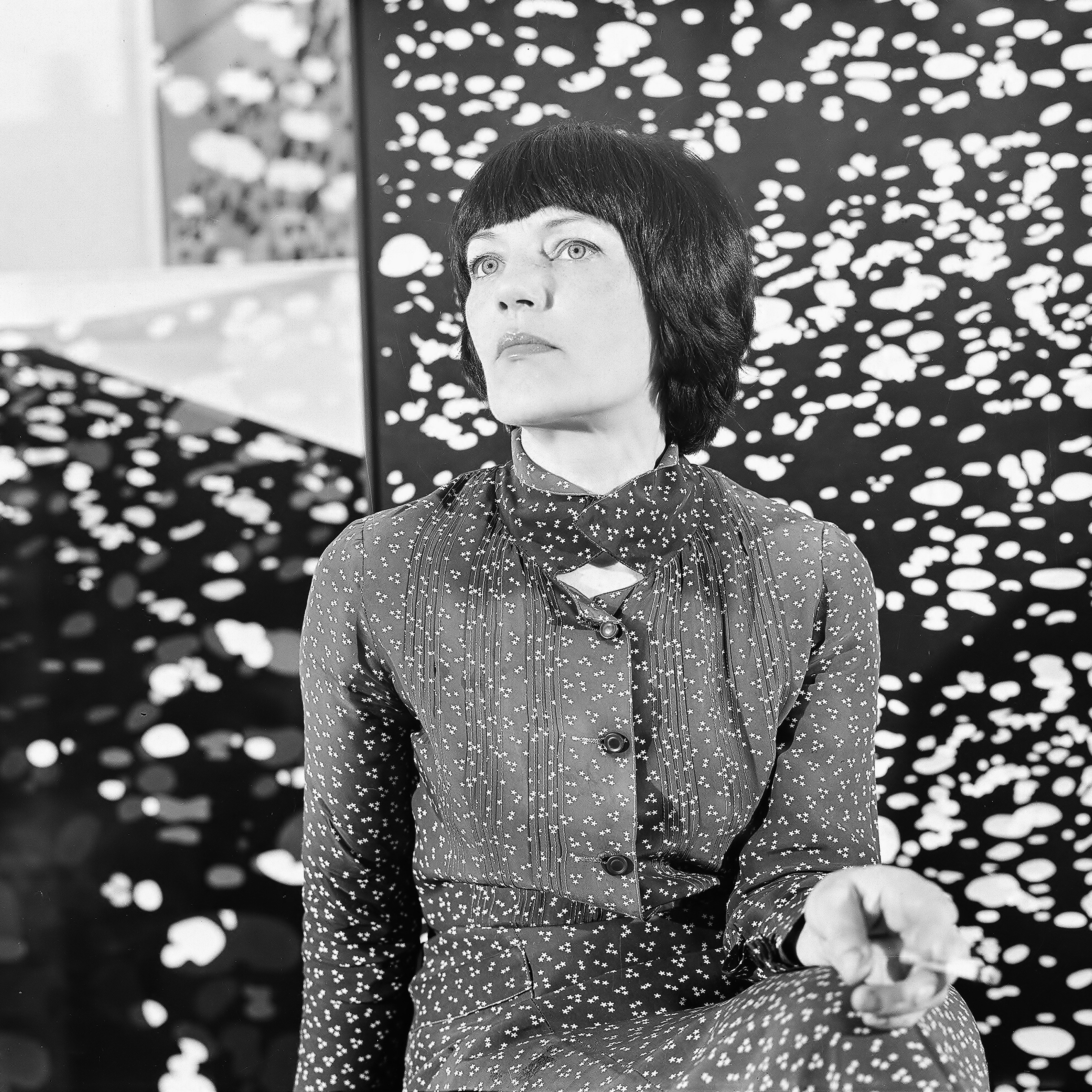 artystyczna fotografia czarno-biała łodej kobiety w stroju w goszki, patrzącej w lewą górną stronę, tło we wzór czarno-biały